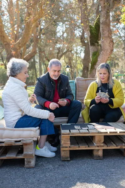 Older adults gathered around a craft table at an adult day program with sunlight through the windows