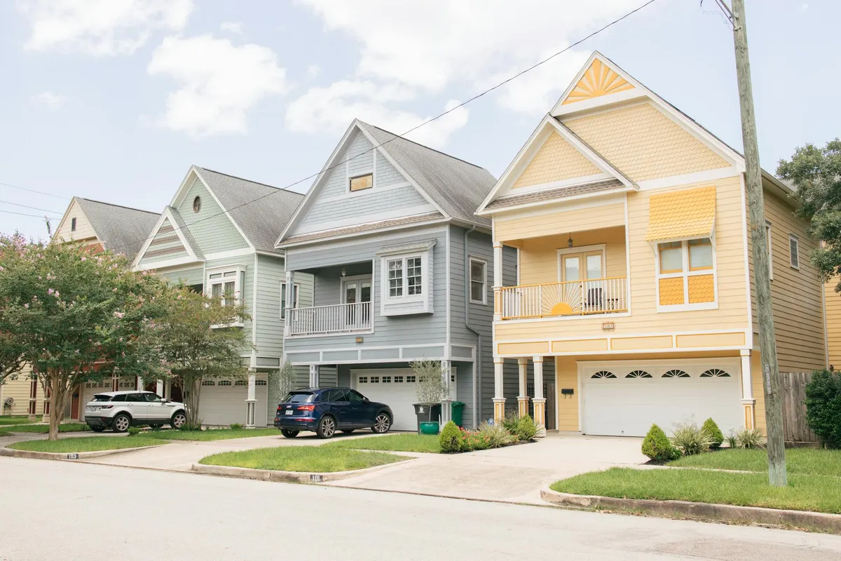 Two side-by-side residential houses on a tree-lined street, both with welcoming front porches.
