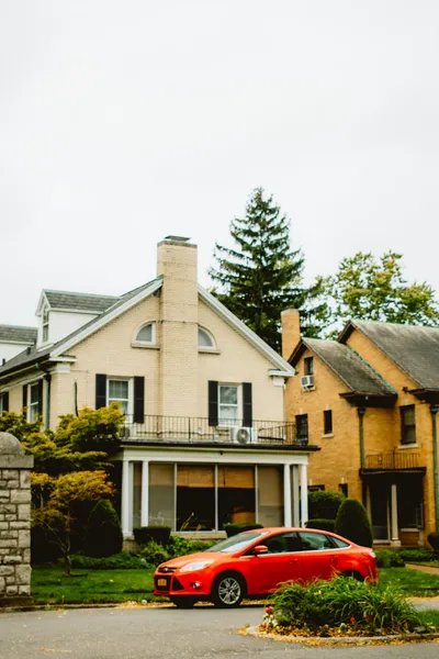 Two homes side by side: a warm residential house on one side and a larger multi-story community building on the other.