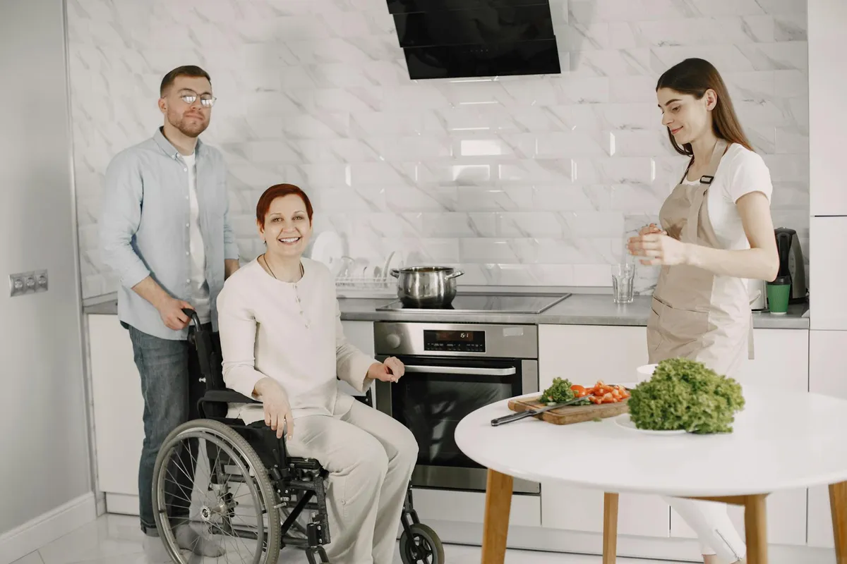 A caregiver and an elderly resident laughing together at a dining table in a small home.