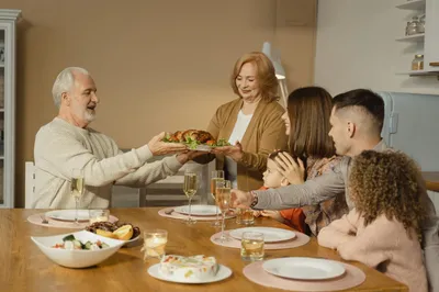 A table set with traditional dishes from multiple cultures, with hands reaching to share food.