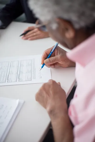 A pile of Medicare paperwork on a kitchen table next to a cup of coffee and a calculator.