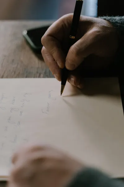 A woman writing notes at a desk with a phone and a printed complaint form beside her.