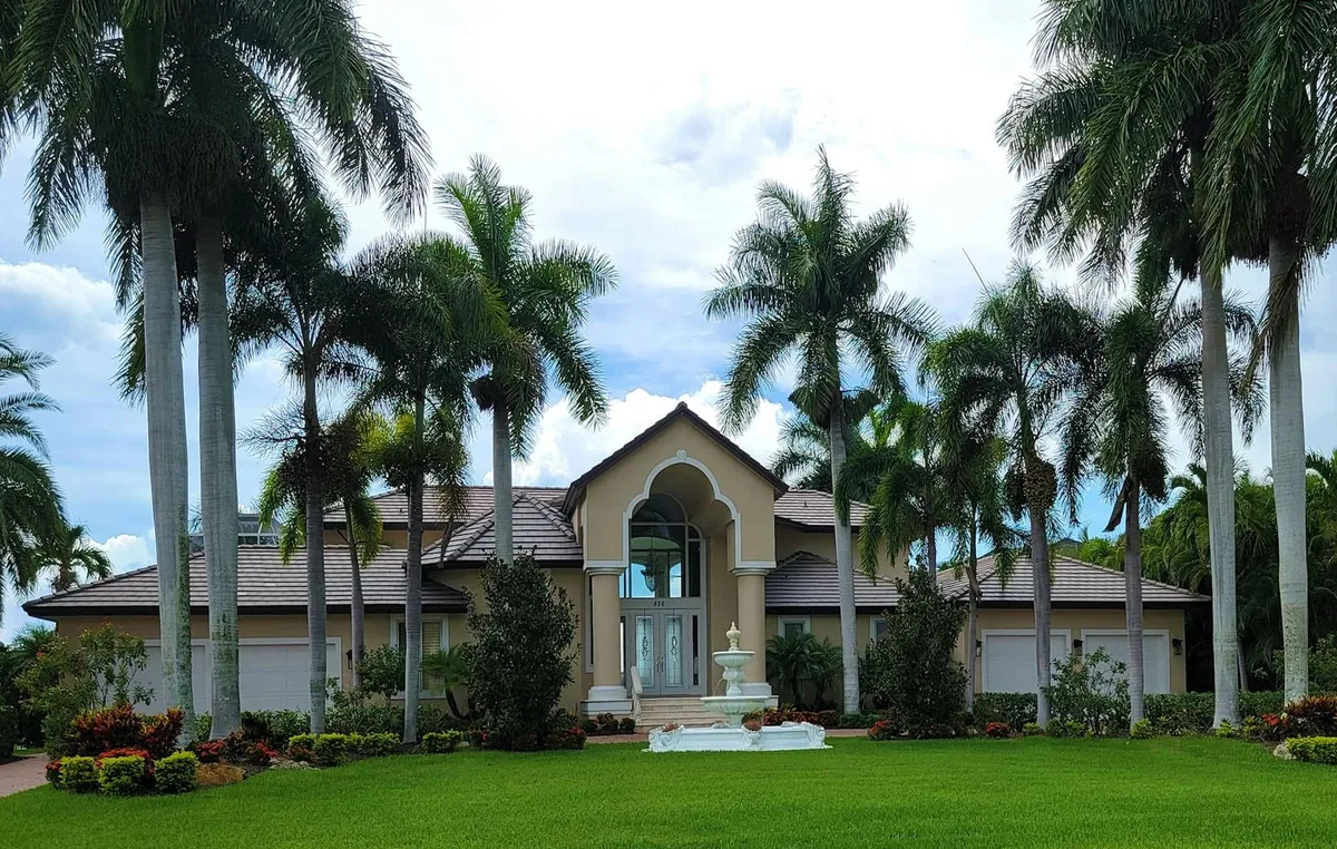 A Florida ranch-style home with palm trees and a screened front porch.