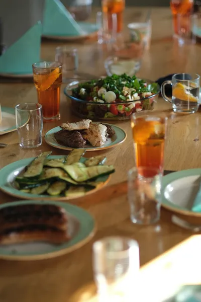 A dining table set for four with home-cooked food, cloth napkins, and a vase of fresh flowers.