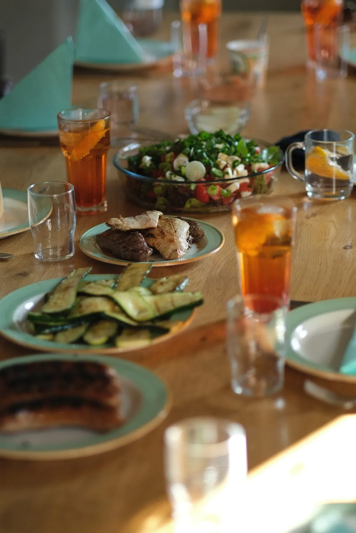 A dining table set for four with home-cooked food, cloth napkins, and a vase of fresh flowers.