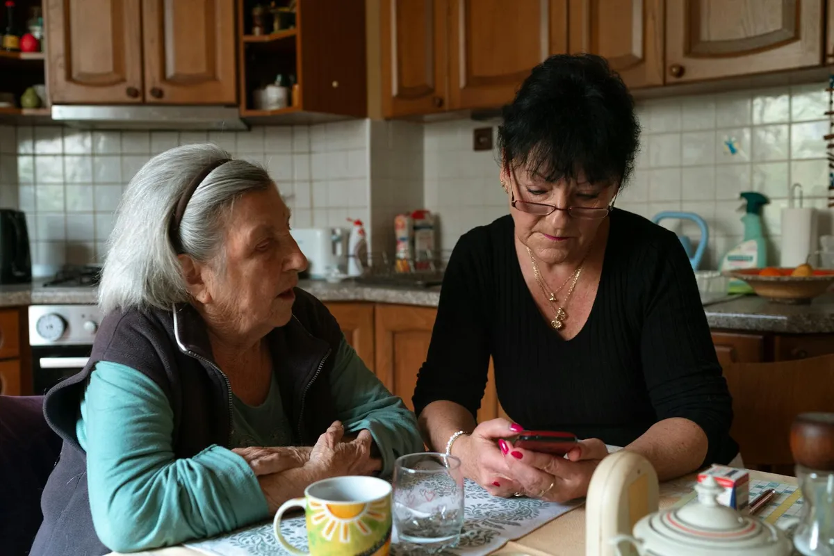 A care home operator and a new caregiver shaking hands at the front door of a small residential home.