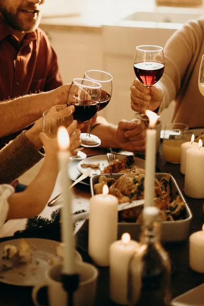 A small dining table set for a holiday meal with candles, flowers, and place settings for four in a sunlit room.