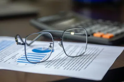 A printed state inspection report on a wooden desk next to a pen and a cup of coffee.