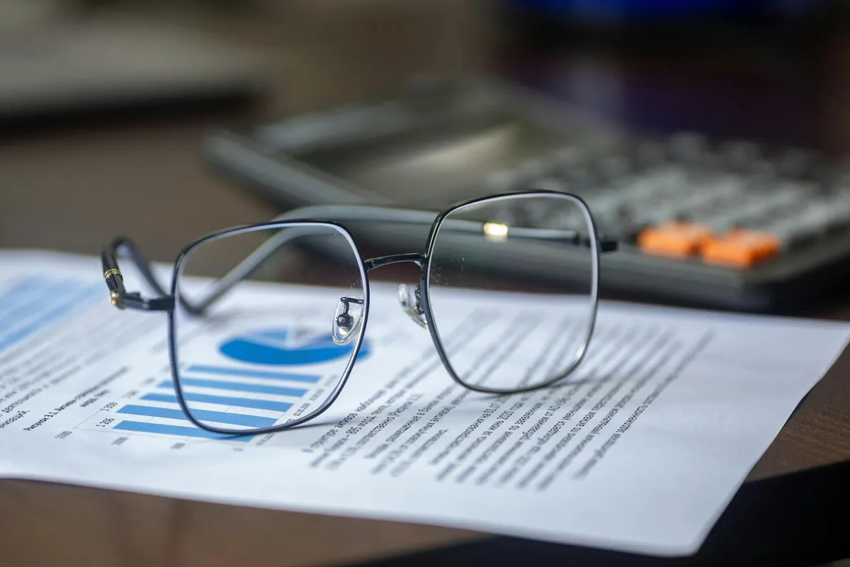 A printed state inspection report on a wooden desk next to a pen and a cup of coffee.