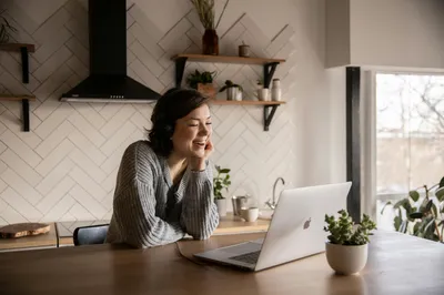 A laptop showing a video call with multiple family members, set on a dining table with notes.