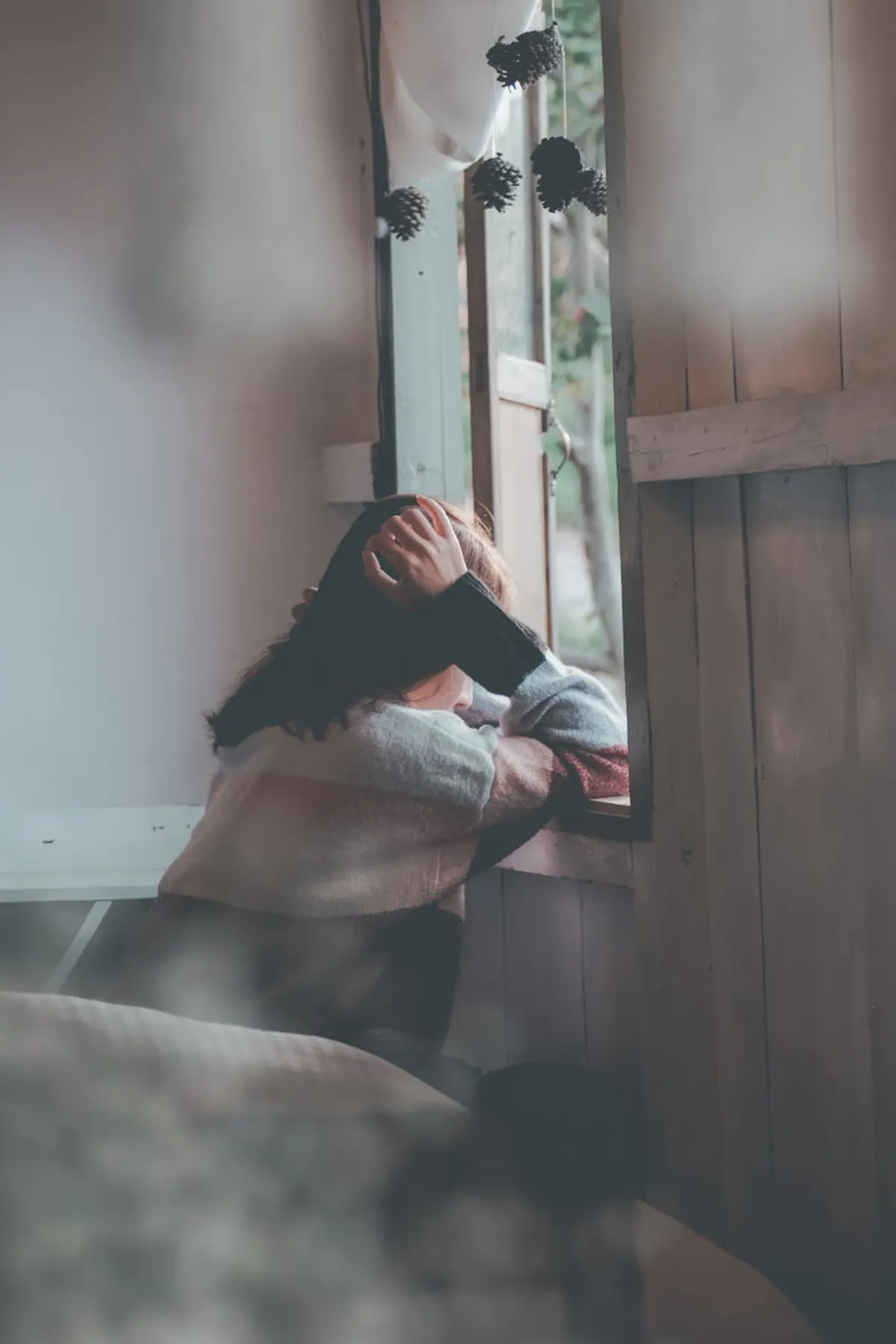 A woman sitting on a front porch at dusk, looking out at a quiet street, a mug in her hands