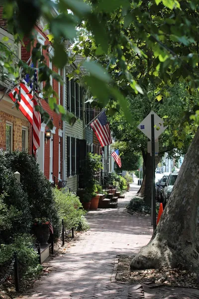A brick colonial home in a Maryland neighborhood with dogwood trees blooming in the front yard.