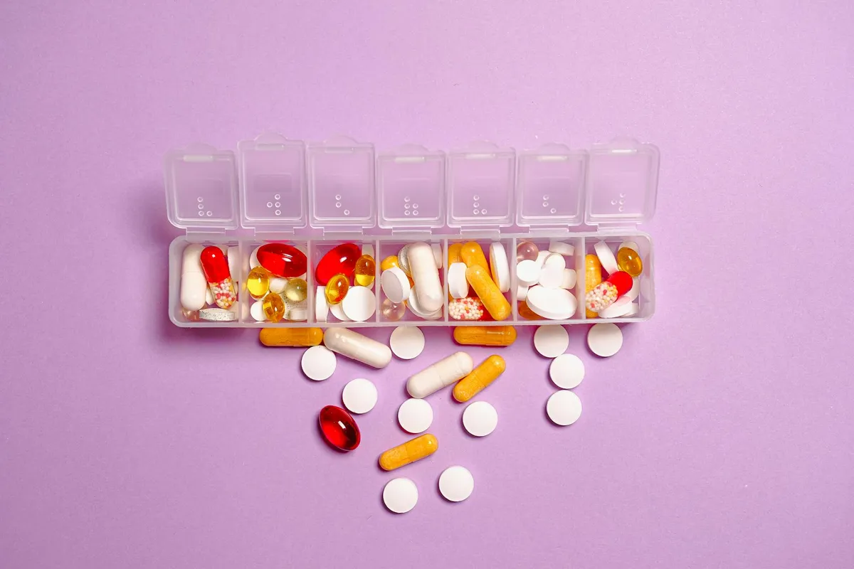 A labeled medication organizer on a clean counter next to a glass of water and a care plan binder.