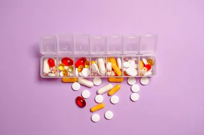 A labeled medication organizer on a clean counter next to a glass of water and a care plan binder.