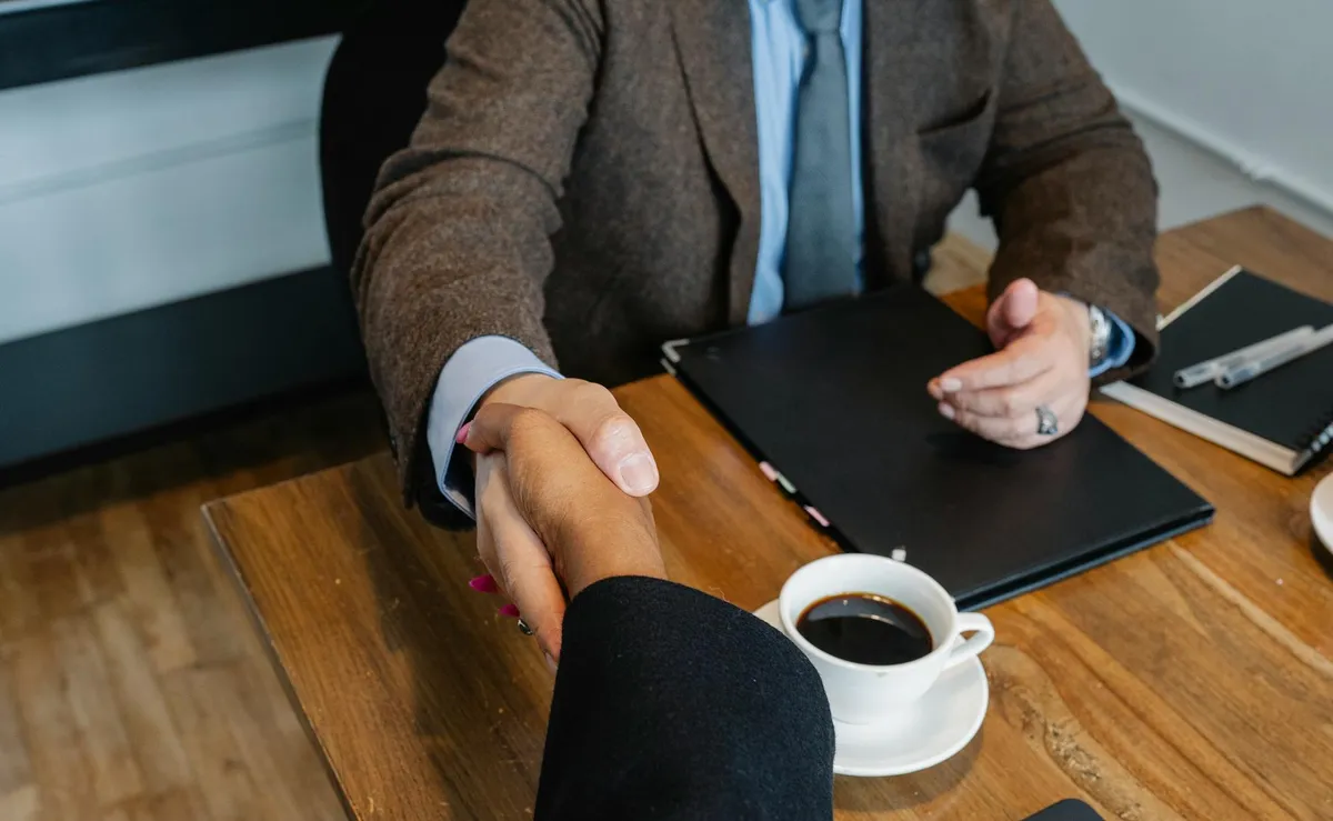 Two people sitting at a kitchen table reviewing paperwork together with a cup of coffee.