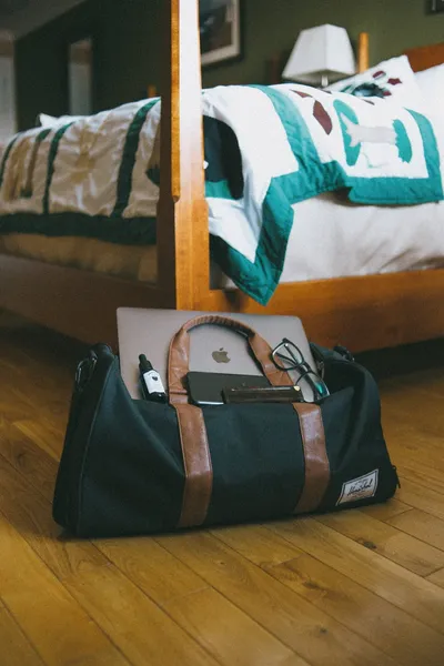 A suitcase open on a bed in a bright guest room with fresh flowers on the nightstand.