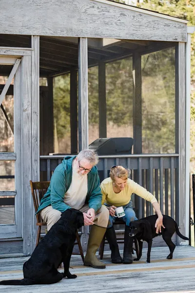 An older couple sitting on the front porch of their home reviewing financial paperwork.