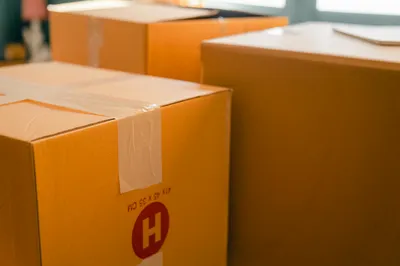 Labeled boxes stacked beside a carefully wrapped family photo on a dining table