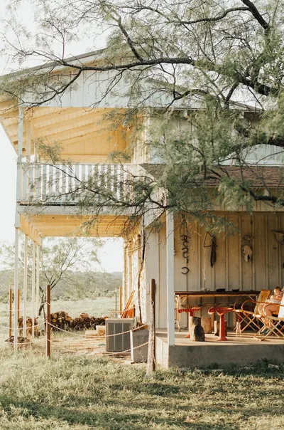 A Texas ranch-style home with a wide front porch and live oak trees in the front yard.