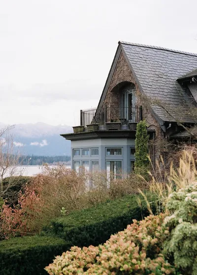 A small craftsman-style home with a covered front porch and a flower garden in the front yard.