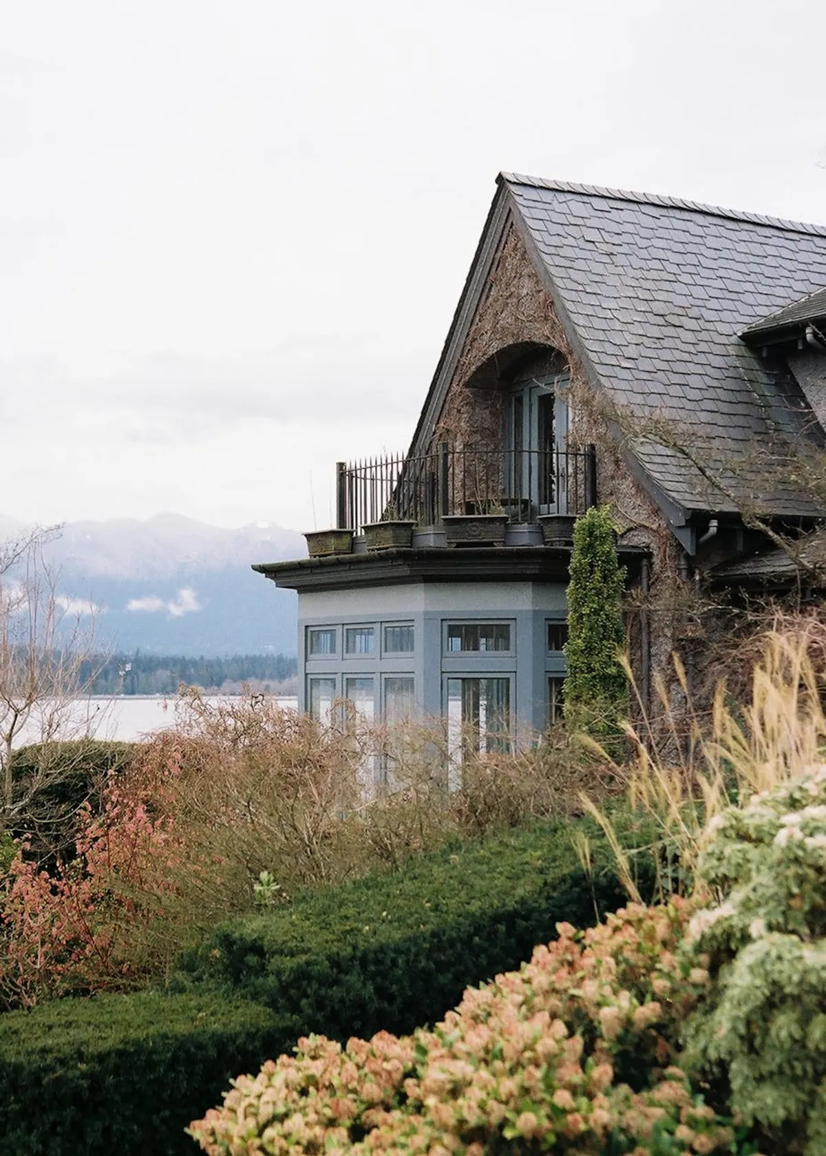 A small craftsman-style home with a covered front porch and a flower garden in the front yard.